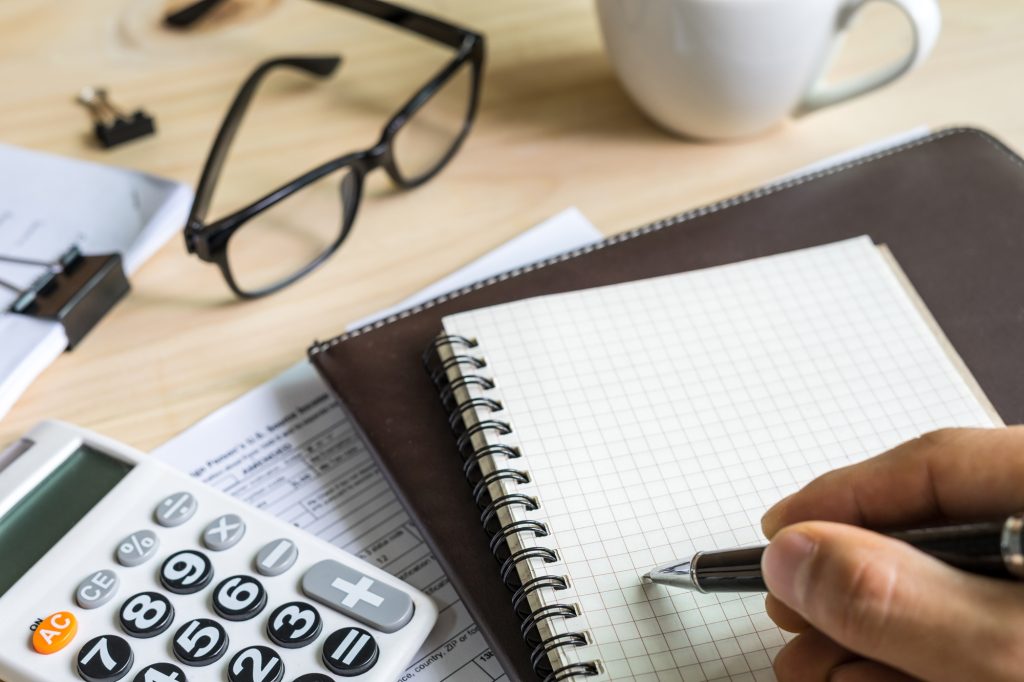 young man hand using calculator and writing
