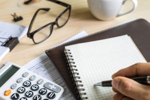 young man hand using calculator and writing